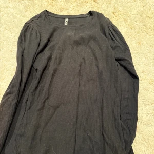 Svart ribbad tröja från Pieces XS - En svart ribbad tröja från Pieces i storlek XS. Tröjan har lång ärm och rund halsringning, med en enkel och stilren design som passar perfekt till många olika looks.