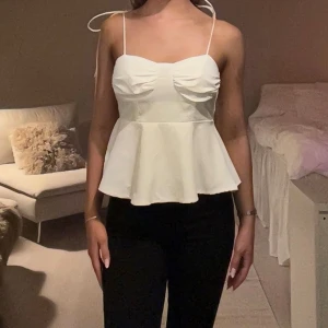 Vit peplum linnetopp med knytband - Säljer en söt vit linnetopp med peplumskärning och smala axelband som knyts på axlarna. 