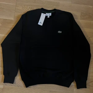 Lacoste - Sweatshirt  - Lacoste sweatshirt i grym kvalité. Fick den som present från min farbror som köpte flera på stor rea utomlands - kvitto finns ej. QR-koden på insidan går direkt till Lacostes hemsida och den är helt ny. Superren modell, passar till allt.  Pris kan diskuteras