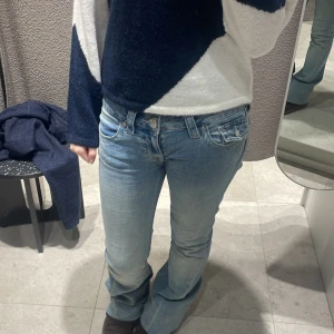True Religion Joey Low Rise Flare Jeans - Säljer ett par ikoniska True Religion Joey jeans i ljusblå tvätt med låg midja och utsvängda ben. Klassiska detaljer som markerade sömmar, snygga bakfickor med lock och silverfärgade knappar. Perfekta för dig som gillar en retro och trendig look.  Dem är nästan helt nya endast avspända ett fåtal gånger Skriv för fler bilder/frågor! ⚠️INTRESSEKOLL⚠️