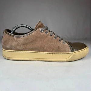 Lanvins Sneakers Bruna   - Snygga bruna sneakers med ovandel i mocka och lackad mörkbrun tå. Skorna har grå snörning och en beige platt sula som ger en clean look. Perfekt för dig som gillar stilrena detaljer och jordnära färger. Orginalbox eller Dustbag ingår ej. Nypris 5500kr+. Skick 8/10. Priset är absolut inte hugget i sten! Skriv om du har frågor så svarar vi snabbt och ärligt! //MvH By, Olsén, Closet.