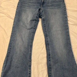 Blå bootcut jeans från Gina Tricot - Snygga ljusblå jeans från Gina Tricot i bootcut-modell. Jeansen har klassisk femficksdesign, dekorativa sömmar på bakfickorna och är tillverkade i mjukt denimtyg. Perfekta för dig som gillar en avslappnad och trendig look.