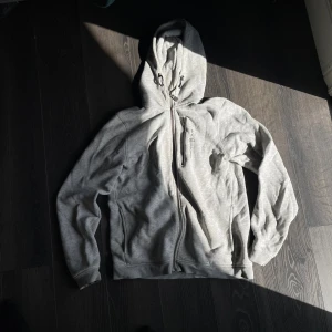 Ljusgrå hoodie från sail racing - Säljer en ljusgrå hoodie med hel dragkedja och huva med snörning. Tröjan har tre fickor med dragkedja och är långärmad. Perfekt för dig som gillar en clean och sportig stil.