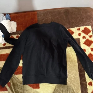 Svart sweatshirt från 157 - En stilren svart sweatshirt från 157 med rund hals och långa ärmar. Tröjan har ribbade muddar vid hals, ärmslut och nederkant. Perfekt för dig som gillar enkel och clean look. Materialet känns mjukt och bekvämt mot huden.