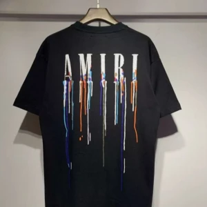 Svart AMIRI t-shirt med färgstänk - Svart t-shirt från AMIRI med stort vitt logotryck på ryggen och coola färgstänk i blått, orange och vitt som rinner ner. Klassisk passform och korta ärmar, perfekt för en edgy streetstyle-look. Priset är inte skrivit i sten och kan diskuteras vid snabb affär, för andra tankar eller så skriv bara 