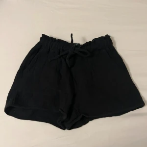 Svarta shorts från FB Sister med snörning - Svarta, lösa shorts från NewYorker i storlek XXS. De har elastisk midja med snörning och är gjorda i ett mjukt, bomullsliknande tyg. Perfekta för varma dagar när du vill ha något bekvämt och enkelt. Pris kan diskuteras! 🥰