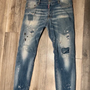 Dsquared2 blå jeans - Säljer ett par blå jeans från Dsquared2 med coola slitningar, hål och färgstänk design från Italien. Nypris ligger runt 4000 storlek 50Y vilket motsvarar ungefär 32-33w priset ej hugget i sten kom med bud. Obs ända defekten är att det har funnits ett hål i mellan skrevet men är fixat och syns då länge inte vid användning 