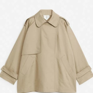 Beige trenchcoat med oversized passform - Supersnygg kort trench coat från ARKET i XS. Oversized i storleken och också sitter toppen på mig som normalt har S. Enbart använd fåtal gånger. Nypris: nästan 2000 kr