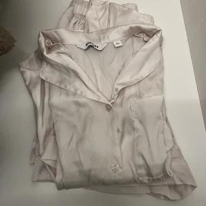 Silkepyjamas  - En vit pyjamas i silke med både shorts och en skjorttshirt! Använd en gång, är för liten nu så tänker sälja. För båda 250kr, för bara shortsen/tröjan 150kr