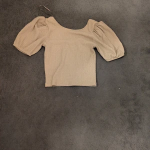 Beige puffärm blus med struktur - Säljer en beige blus med puffiga korta ärmar och fyrkantig halsringning. 