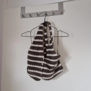 Randig brun och vit stickad halterneck - Snygg topp från Amisu. Knyts vid nacken och knapparna på framsidan av toppen går att knäppa upp. Storlek M men den är liten i storleken och är inte stretchig så den skulle är mer en XS eller kanske S. Jag har storlek S-M i toppar och den var för liten för mig. Katt finns i hemmet.