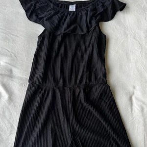 Svart jumpsuit med volang - Svart plisserad jumpsuit med volang från Lindex.  Storlek: 146/152. Fraktar inom 24h!