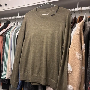 Zadig Voltaire tröja - Olivgrön långärmad tröja från Zadig & Voltaire i mjuk kashmirmix. Rund hals med broderad text 'WE SHOULD KISS' vid kragen som ger en cool detalj. Stilren och enkel design med ribbade muddar och avslappnad passform. Perfekt för dig som gillar minimalistisk vibe. Helt oanvänd, köpt för 4000kr+. S sitter som M.