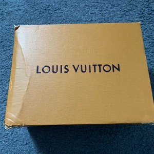 Louis Vuitton Damier handväska brun - Superfin liten handväska från Louis Vuitton i klassiskt brunt Damier-mönster. Väskan har guldfärgade metalldetaljer, mörkbruna handtag och avtagbar axelrem. Tillverkad i canvas med skinn-detaljer och beige insida. Kommer med originalkartong och kvitton.