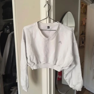 Vit croppad sweatshirt med v-ringning Oner Active -  En vit croppad sweatshirt från Oner Active med v-ringad hals och långa ärmar. Tröjan har en relaxed passform och ribbade muddar vid ärmslut och nederkant. 