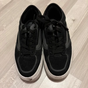 Svarta Vans Old Skool sneakers - Svarta Vans Old Skool sneakers med klassisk vit sula och grå sidostripes. Skorna har snörning och är tillverkade i mocka och syntetmaterial. Rund tå och platt sula ger en skön streetstil. Perfekta för dig som gillar skate och avslappnad look.  Har använd de många gånger 