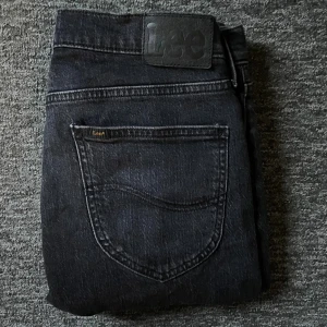 Svarta jeans från Lee, modell West W29 L32 - Säljer ett par svarta jeans för endast 250kr ,ord pris 999kr. Jeansen är ifrån Lee, modell West i storlek W29 L32. Jeansen har klassisk femficksdesign, Lee-logga på bakfickan och är tillverkade i bomull. Snygg, mörk tvätt och rak passform som funkar till många stilar. Hör gärna av er om ni har någon fråga 