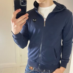 CDG play full zip mörkblå  - CDG play full zip mörkblå med svart logga i storlek S. Väldigt skön, och väldigt bra passform! Inga defekter✌️ modellen är 180 cm 75 kg. Btw är snöret utdraget ur själva luvan, det går att fixa men lite drygt kanske. 