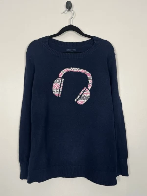 Tommy Hilfiger stickad tröja med hörlursmotiv (finstickad) - Tommy Hilfiger stickad tröja med hörlursmotiv i navy Storlek: L Färg: Mörkblå (navy) med rosa, beige och grått motiv Passform: Regular fit  Krage: Rund hals (crew neck) Material: 35 % bomull, 33 % nylon/polyamid, 30 % polyester & 2 % akryl Skick: Denna tröja är i ett väldigt fint skick utan defekter  Nypris cirka: 1 400 kr