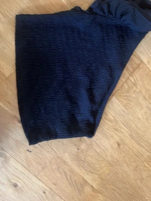 Svart ärmlös topp från SHEIN - Stilren svart topp från SHEIN i stretchigt tyg med struktur. Toppen är ärmlös och har en åtsittande passform som ger en modern look. Materialet består av 96% polyester och 4% elastan vilket gör den både bekväm och följsam.