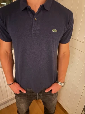 Mörkblå pikétröja från Lacoste - Klassisk mörkblå pikétröja från Lacoste med krage.