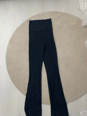 Svarta utsvängda leggings - Säljer ett par svarta leggings med hög midja och utsvängda ben. De är mjuka och stretchiga, perfekta för en avslappnad och trendig look. Passar dig som gillar bekväma men ändå snygga byxor till vardagsstilen.