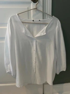Vit blus  - Stilren vit blus med knäppning framtill. Blusen har en avslappnad passform och trekvartsärmar med lätt puff vid ärmslut. Perfekt att matcha med jeans eller kjol för en fräsch look. Lappen är bortklippt så är osäker vart den är ifrån 