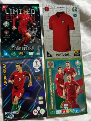 Fotbollssamlarspel Portugal-kort - Fyra samlarkort från ett fotbollsspel med portugisiska landslaget. Motiven inkluderar spelare i röd matchtröja, ett kort med en röd Portugaltröja och flera kända spelare. Kortens design är färgstark med holografiska effekter och statistik.
