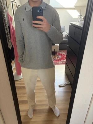 långärmad polo tröja - Säljer en stilren grå långärmad pikéskjorta med krage och knappar framtill. Tyvärr har den ingen tagg i nacken så vet inte storleken men skulle säga att den passar som en M. Jag är 180 70kg och den är lite stor på mig 