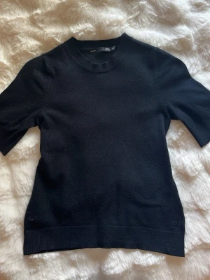 Svart topp från 157 med kort ärm - En enkel svart topp från 157 med rund halsringning och korta ärmar. Tillverkad i mjukt material som känns skönt mot huden. Perfekt att styla med jeans eller kjol för en clean look.