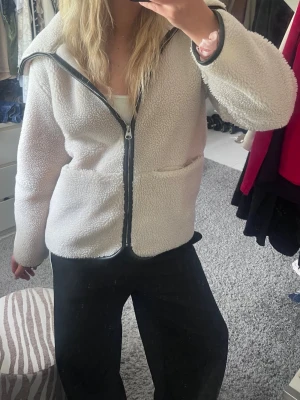 Beige teddyjacka från Arket - Mysig beige teddyjacka med svart dragkedja och två stora fickor framtill, från Arket. Jätte fint skick!! 