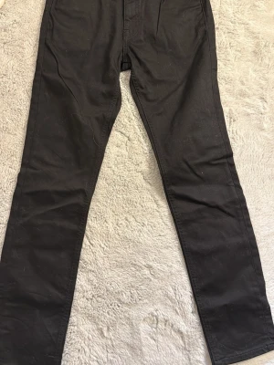 Svarta slim jeans 30/32 - Svarta slim fit jeans med klassisk femficksdesign och dragkedjegylf. Jeansen har en smal passform och är tillverkade i ett stretchigt material för extra komfort. Perfekta för en stilren och enkel look.