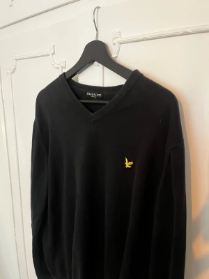 Svart V-ringad Vintage tröja Lyle & Scott - Klassisk svart V-ringad tröja från Lyle & Scott. Tröjan har långa ärmar och är tillverkad i mjukt material så den sitter tajt bra på en, tröjan är även ett så kallad Vintage plagg av Lyle & Scott. Inga skador på tröjan!