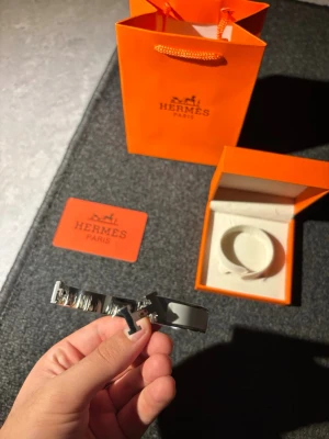 Hermès armband - Snyggt vitt armband från Hermès med silverfärgad metall och den ikoniska H-detaljen framtill. Armbandet har en stilren och modern design som passar perfekt till din outfit. Kommer med originalförpackning och påse.