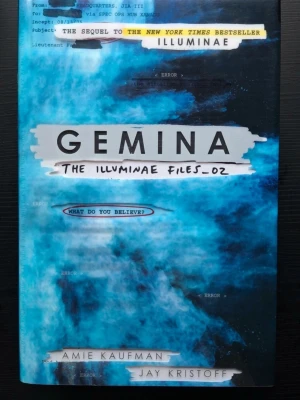 Gemina - The Illuminae Files 2  - En spännande science fiction-roman med blått och svart omslag, skriven av Amie Kaufman och Jay Kristoff. Boken är andra delen i The Illuminae Files-serien och har ett unikt grafiskt omslag med textinslag och futuristisk känsla. Perfekt för dig som gillar action och äventyr. Ca 600 sidor, inbunden