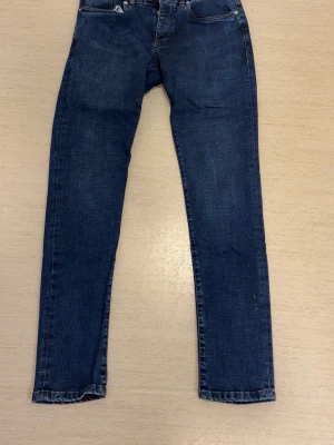 Mörkblå raka jeans Arsam Exclusive - Mörkblå jeans från Arsam Exclusive med raka ben och klassisk femficksdesign. Jeansen har knappgylf och är gjorda i slitstarkt denimtyg. Perfekta för dig som gillar en enkel och stilren look.
