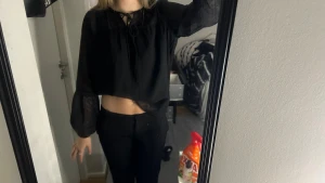 Svart blus med snörning och vida ärmar - Säljer en svart blus med transparenta, vida långärmar och snörning vid halsen. Blusen är croppad och har en lös passform som ger en avslappnad men ändå trendig look. Perfekt att styla med höga byxor eller kjol.