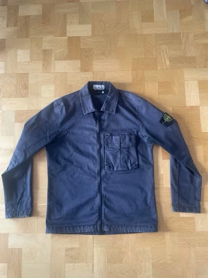 Stone Island Overshirt  - En Stone Island ”Old Effect” Overshirt från SS’23. Den är i mycket bra skick, nästan som ny. Den enda tydligt synliga defekten syns i bild 4, lappen har lossnat i ena änden. Storlek: M. Färg: Navy