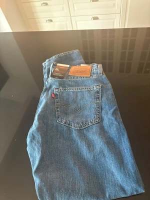 Levi's 512 Slim Taper blå jeans - Säljer ett par Levi's 512 Slim Taper jeans i klassisk blå denim. Modellen har smal passform med avsmalnande ben och stretchigt material för extra komfort. Tillverkade i en lättviktsmix av linne och denim. Perfekta för en avslappnad men snygg look.