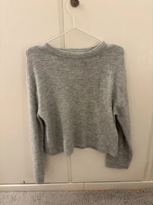 Ljusgrå stickad tröja från 157 - Mysig ljusgrå stickad tröja från 157 med rund halsringning och långa ärmar. Tröjan har en enkel och clean design, perfekt att matcha med jeans eller kjol. Materialet känns mjukt och bekvämt mot huden.