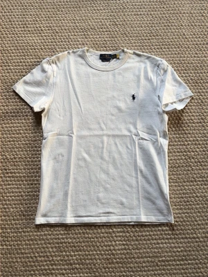 Vit t-shirt från Ralph Lauren - Vit klassisk t-shirt från Polo Ralph Lauren med rund halsringning och broderad marinblå logga på bröstet | Storlek S-XS | Fraktas inom 1 dag.