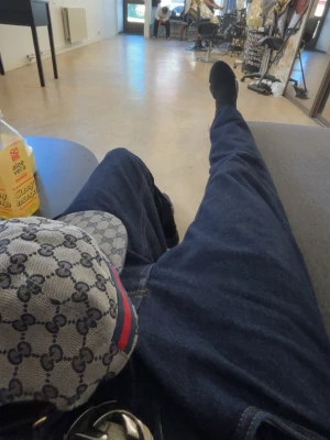 Gucci keps med monogram och röd-blå rand - Säljer en snygg Gucci keps i grått med klassiskt GG-monogram över hela kepsen och en röd-blå rand på sidan. Kepsen är i ett tåligt tygmaterial och har en böjd skärm. Perfekt för dig som vill ha en stilren accessoar med lyxig känsla. Behövs en tvätt akut men lätt fixat med en tvättpåse 