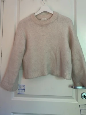 Beige mohairtröja från H&M - Mysig beige stickad tröja från H&M i mohair- och ullblandning. Tröjan har rund halsringning, långa ärmar och ribbade muddar vid ärmslut och nederkant. Perfekt för lager på lager och en clean look.