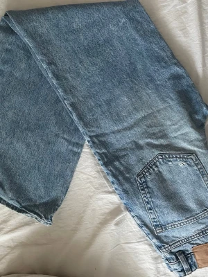 Blåa raka jeans med slitningar - Säljer ett par blåa jeans med raka ben och hög midja, jeansen har slitna detaljer på framsidan🩵