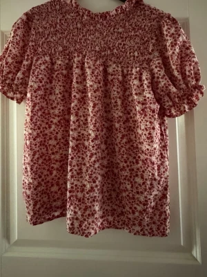 Blommig puffärm blus i rosa och vitt - Söt blus   med puffiga korta ärmar och smock upptill. Blusen har ett blommigt mönster i rosa och vitt, samt en lös och luftig passform. Har använt den cirka fyra gånger 
