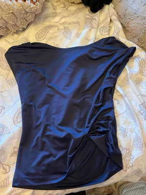 Marin blå topp med öppen rygg!💙 - Mörkblå topp i glansigt  material med öppen rygg.perfekt för alla lägen!!Storlek M.och köpt i Spanien! Använd någon enstaka gång.