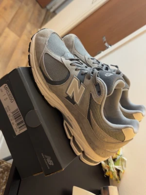 Grå New Balance 990v5 sneakers - Snygga grå New Balance 990v5 sneakers med klassisk siluett. Ovandel i mocka och mesh för både stil och andningsförmåga. Ikoniskt N på sidan och bekväm sula som passar perfekt till streetwear och casual outfits. Helt helt nya, dock använda en gång bara vilket ni redan ser, 