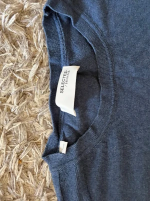 Blå tröja  från Selected Homme - En stilren blå tröja  från Selected Homme i mjuk bomull. Klassisk rund halsringning och normal passform. Perfekt basplagg till garderoben. Tveka inte och höra av dig i dms 