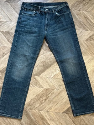 Levi's 505 - Snygga blå jeans med raka ben och klassisk femficksmodell. Jeansen har en något tvättad look och detaljer som metallknapp och dragkedja. Materialet är denim i bomull och de har en tidlös stil som funkar till det mesta. Längd 111cm Bredd 44cm