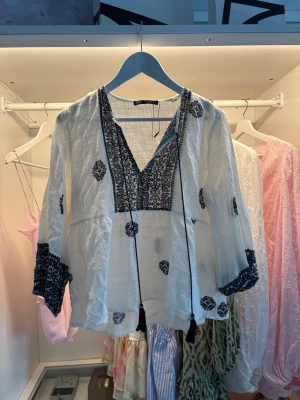 Vit blus med mörkblå broderier - Jag säljer en vit blus med mörkblå detaljer från Zara. Den är använd men är i ett bra skick. Bara att skriva om du har frågor eller vill ha fler bilder💗